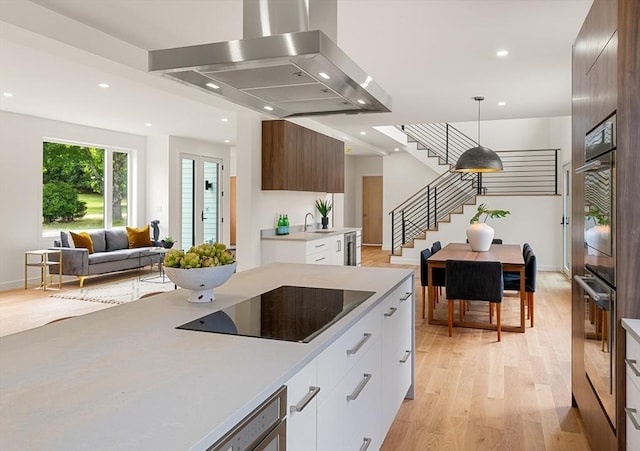 kitchen featuring light countertops, modern cabinets, island exhaust hood, and white cabinetry