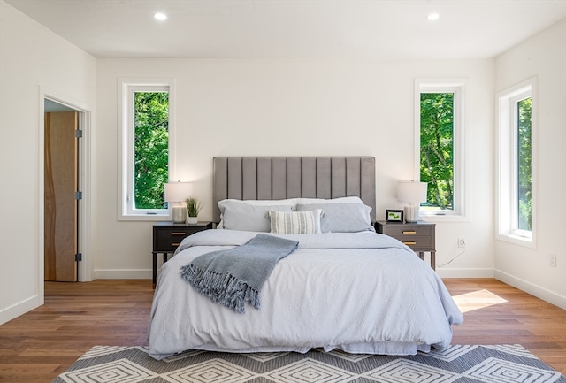 bedroom with hardwood / wood-style flooring and multiple windows