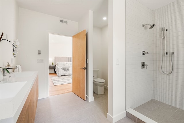 bathroom with tiled shower, hardwood / wood-style flooring, toilet, and vanity