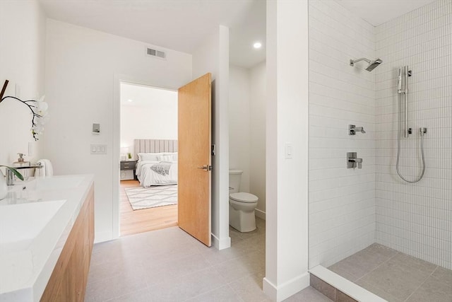 ensuite bathroom with toilet, connected bathroom, visible vents, and a tile shower