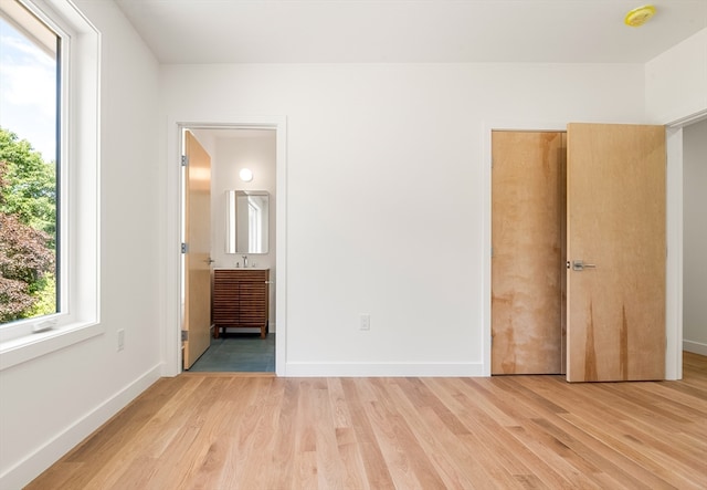 unfurnished bedroom with connected bathroom and light hardwood / wood-style flooring