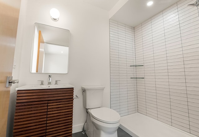 bathroom with tiled shower, vanity, and toilet