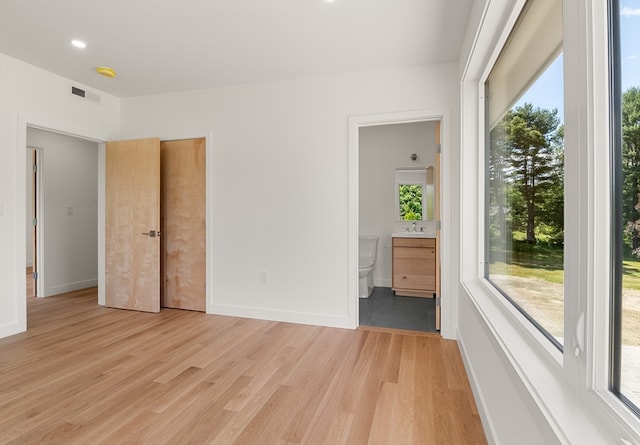 unfurnished bedroom with sink, light hardwood / wood-style floors, and connected bathroom