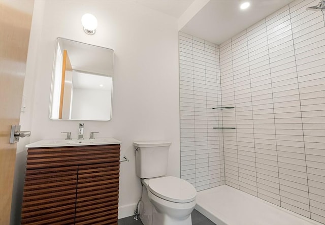 full bath featuring toilet, tiled shower, and vanity