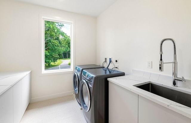 clothes washing area with laundry area, light tile patterned floors, baseboards, washing machine and dryer, and a sink