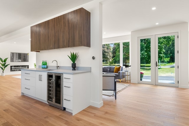 kitchen with wine cooler, white cabinetry, and light hardwood / wood-style flooring