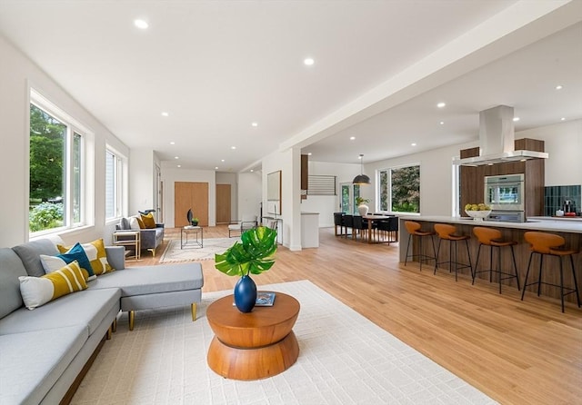 living area with light wood-type flooring, plenty of natural light, and recessed lighting