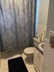 full bath with toilet, tile patterned floors, vanity, and curtained shower