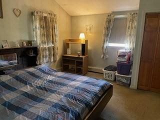 carpeted bedroom featuring vaulted ceiling and baseboard heating