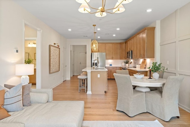 dining space with light hardwood / wood-style floors, sink, and an inviting chandelier