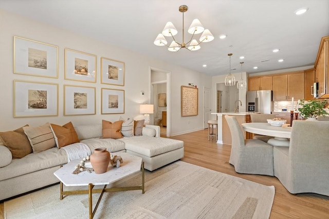 living room with a notable chandelier, sink, and light hardwood / wood-style flooring