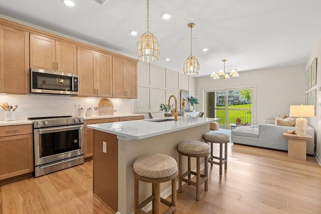 kitchen with pendant lighting, sink, a breakfast bar area, an island with sink, and stainless steel appliances