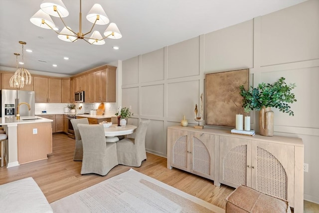 dining space featuring a chandelier, light wood-type flooring, and sink