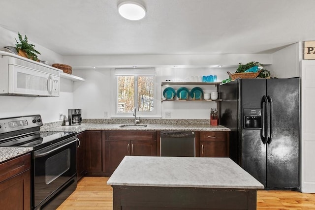 kitchen featuring sink, dark brown cabinets, a center island, black appliances, and light hardwood / wood-style floors