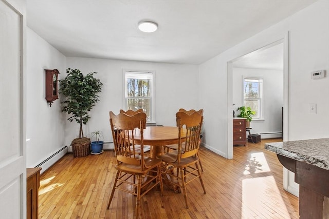 dining space with a baseboard heating unit, a wealth of natural light, and light hardwood / wood-style floors