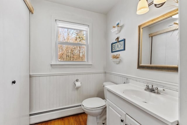 bathroom featuring vanity, wood-type flooring, toilet, and baseboard heating