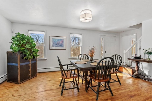 dining space with plenty of natural light, a baseboard heating unit, and light hardwood / wood-style floors