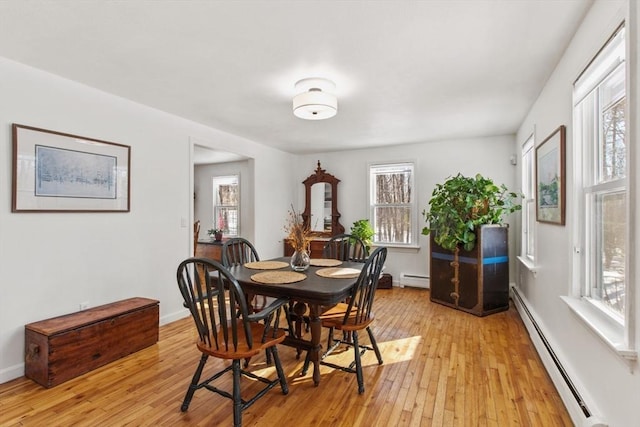 dining room featuring a healthy amount of sunlight, light wood-type flooring, and baseboard heating