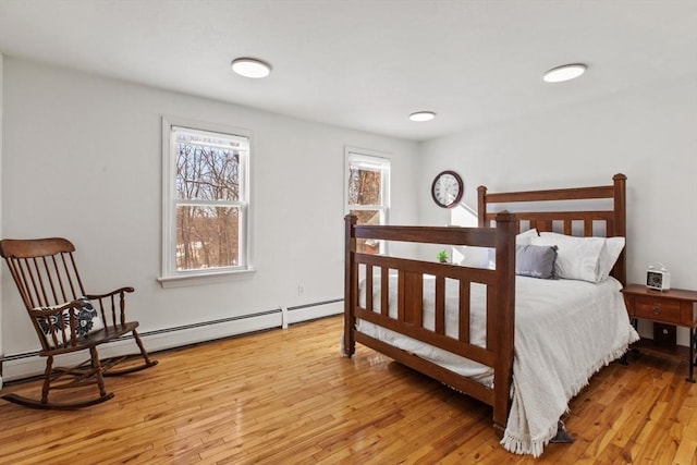 bedroom featuring a baseboard heating unit and light hardwood / wood-style flooring