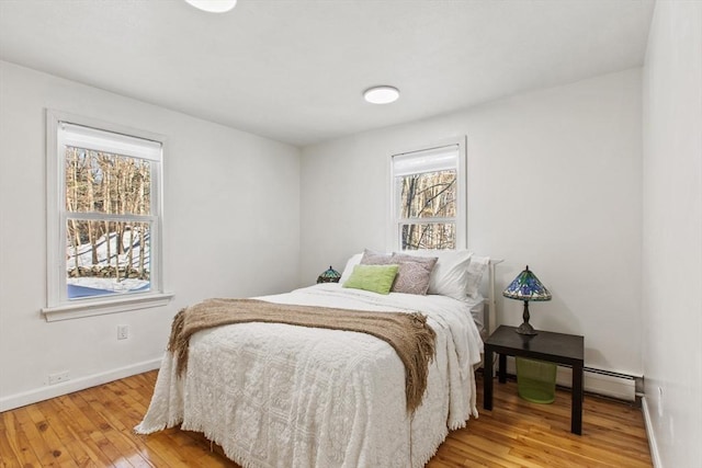 bedroom featuring multiple windows, hardwood / wood-style floors, and a baseboard radiator