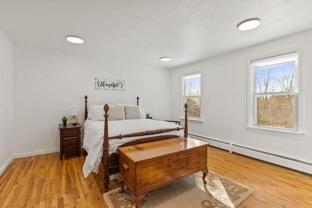 bedroom with baseboard heating and light hardwood / wood-style floors