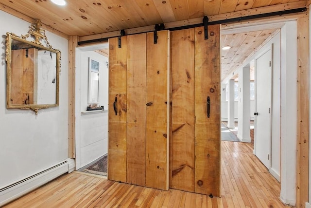 hall with baseboard heating, a barn door, light hardwood / wood-style flooring, and wooden ceiling