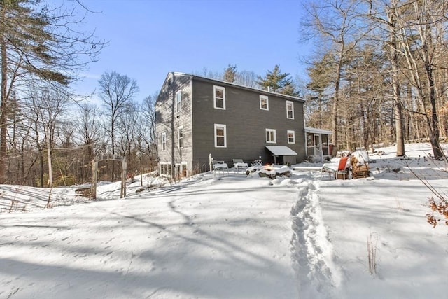 snow covered rear of property with a sunroom