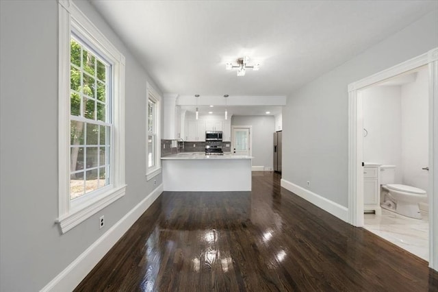 68 Putnam St, Weymouth, MA 02189 - kitchen with appliances with stainless steel finishes, a peninsula, baseboards, dark wood-type flooring, and white cabinetry