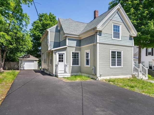 68 Putnam St, Weymouth, MA 02189 - view of front of house with an outbuilding, a chimney, a detached garage, and roof with shingles