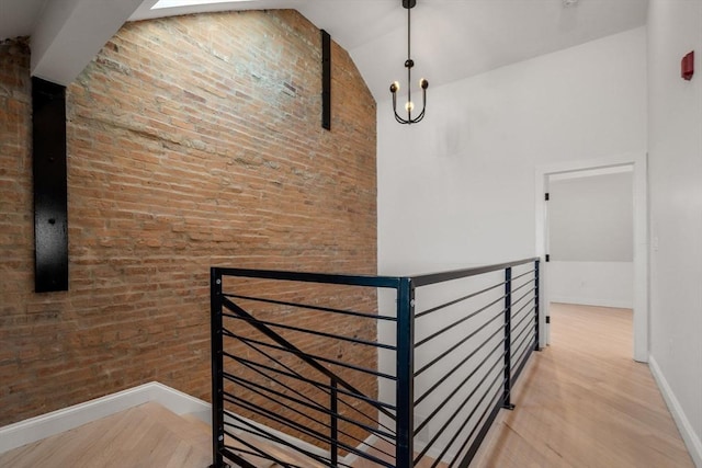 corridor featuring an upstairs landing, high vaulted ceiling, and wood finished floors