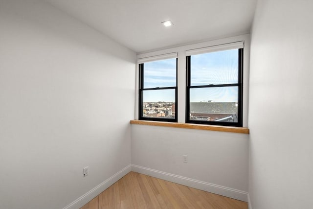 spare room with baseboards and light wood-style floors