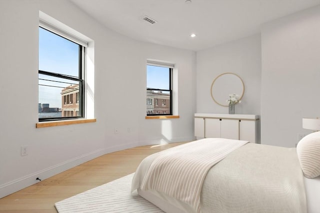 bedroom with multiple windows, wood finished floors, and visible vents