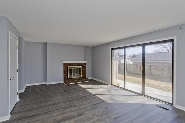 unfurnished living room featuring visible vents, a fireplace, baseboards, and dark wood-style flooring