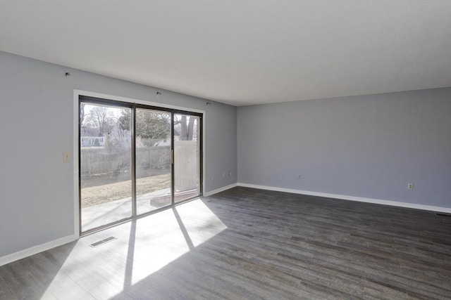 unfurnished room with visible vents, baseboards, and dark wood-style floors