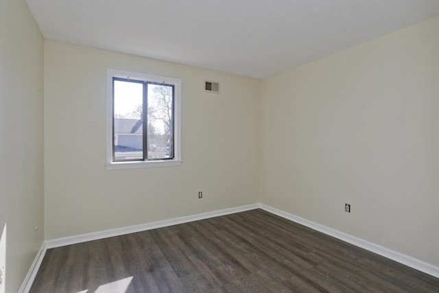 spare room with visible vents, baseboards, and dark wood-style floors