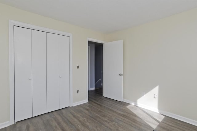 unfurnished bedroom with a closet, baseboards, and wood finished floors