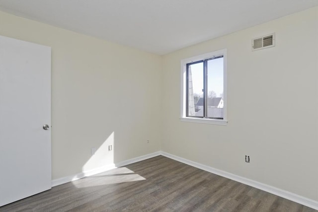 empty room featuring baseboards, visible vents, and dark wood-style flooring