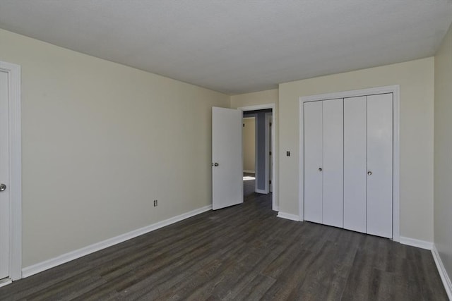 unfurnished bedroom with dark wood-style floors, a closet, and baseboards