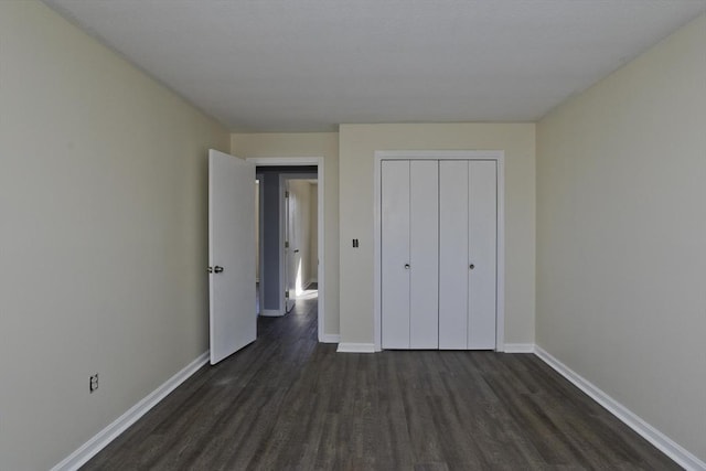 unfurnished bedroom with dark wood-style floors, a closet, and baseboards