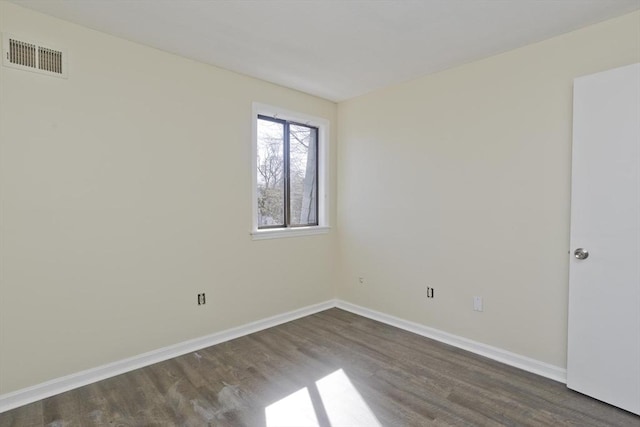 empty room featuring dark wood-type flooring, baseboards, and visible vents