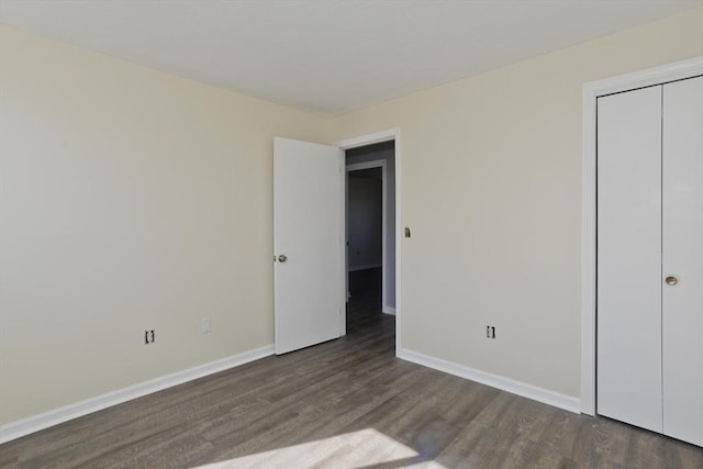 unfurnished bedroom with wood finished floors, baseboards, and a closet