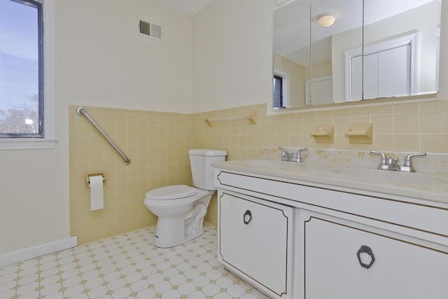 bathroom with double vanity, toilet, visible vents, and a sink