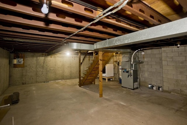 unfinished below grade area featuring heating unit and stairs