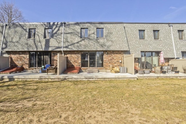 back of property featuring entry steps, mansard roof, a yard, brick siding, and a patio area