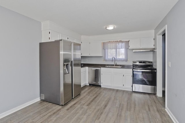 kitchen featuring dark countertops, under cabinet range hood, white cabinets, stainless steel appliances, and a sink