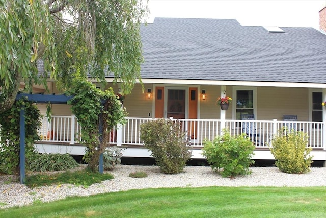 view of front of house featuring covered porch, roof with shingles, and a chimney