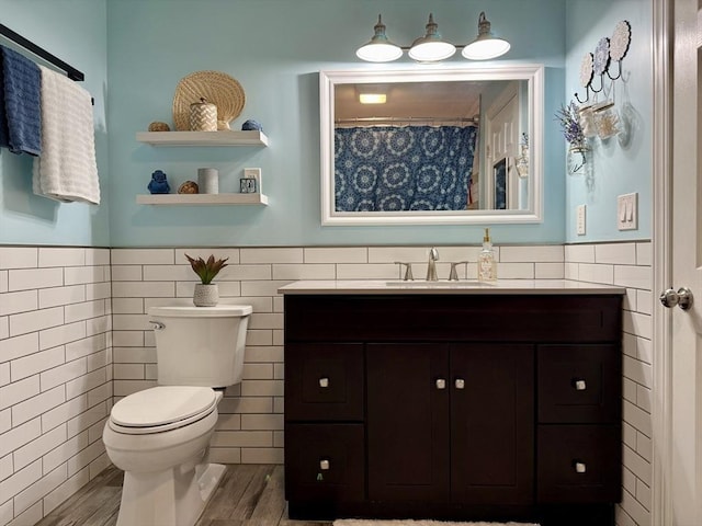 full bathroom with toilet, wood finished floors, tile walls, wainscoting, and vanity