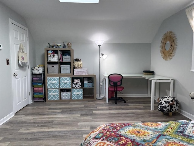 office featuring lofted ceiling with skylight, baseboards, and wood finished floors