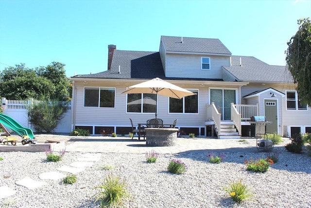 rear view of house with fence, roof with shingles, a chimney, a patio area, and an outbuilding