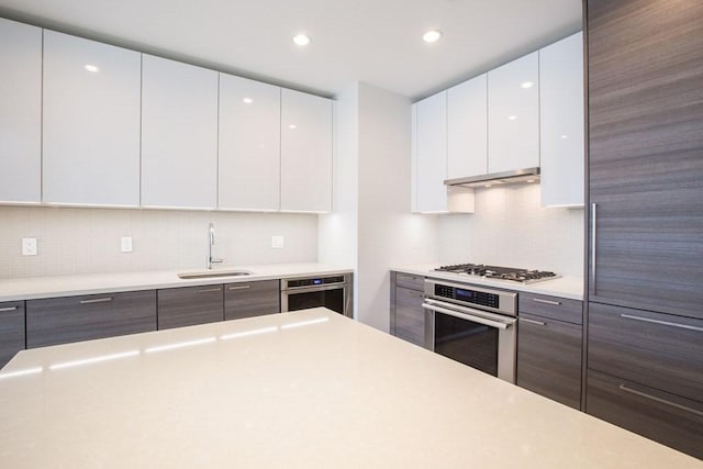 kitchen featuring a sink, stainless steel appliances, light countertops, and white cabinets